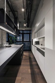 an industrial style kitchen with white cabinets and black counter tops, along with dark wood flooring