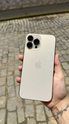 a person holding an iphone in their hand on a brick walkway with cobblestones