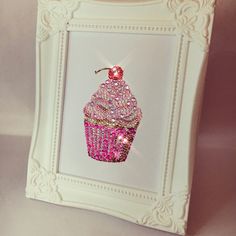 a pink cupcake with a cherry on top is framed in a white ornate frame