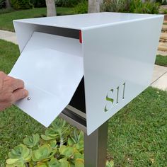 a hand is opening the mailbox to reveal it's letters and numbers,