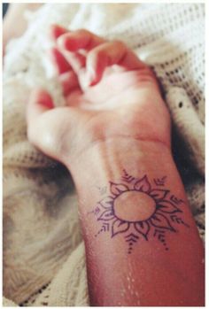 a woman's arm with a sun tattoo on it