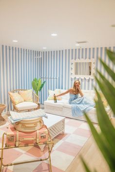 a woman sitting on top of a bed in a room with blue and white striped walls