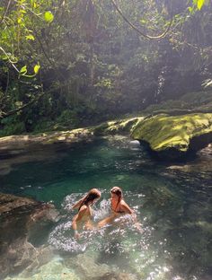 two people swimming in a river surrounded by trees