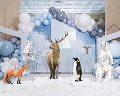 some animals are standing in the middle of a room with blue and white balloons around them