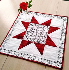 a red and white quilted table runner with a flower on it's side