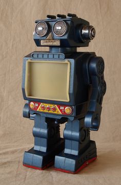 a toy robot that is sitting on top of a brown surface with its eyes open