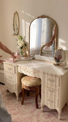 a woman standing in front of a white dressing table