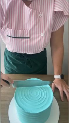 a woman cutting a cake with a knife on top of a white and blue plate