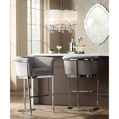 two gray chairs sitting next to each other in front of a table with a chandelier