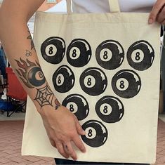 a person holding a tote bag with eight ball designs on it