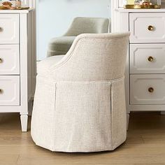 a white chair sitting on top of a wooden floor next to a dresser and mirror