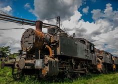 an old rusty train sitting in the grass