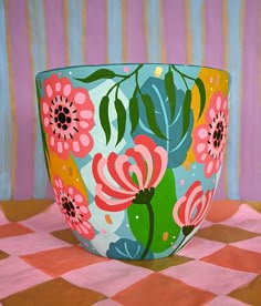 a colorful bowl sitting on top of a checkered tablecloth covered floor next to a pink wall