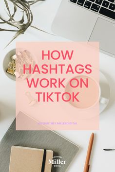 a white desk with a laptop, notebook and pen on it that says how hashtags work on tiktok