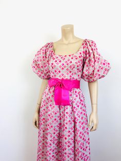 "Vintage 1970s Puff Sleeve Dress - huge puffy sleeves - sits right at shoulders edge - pink satin bow tie at waist - full maxi skirt - zips at back - pink with silvery grey geometric print - sheer chiffon like material, lined designer - amelia gray Great vintage condition, lining has a little discoloration size - S 34\"bust 24\"waist full hip 54\"length All sales are final / as-is. We do not accept returns." Retro Pink Silk Dress, Pink Fairycore Puff Sleeve Dress, Pink Retro Silk Dress, Vintage Pink Puff Sleeve Dress, Pink Silk Retro Dress, Vintage Multicolor Puff Sleeve Dress, Retro Pink Dress With Button Closure, Vintage Pink Dress With Button Closure, Wedding Dresses Hippie