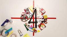 a clock made out of scissors, tape and other items on a white surface with red lines