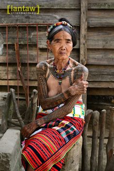 an old woman with tattoos sitting on a bench