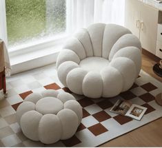 a white chair and ottoman sitting on top of a checkered rug in front of a window