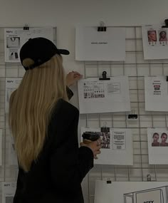 a woman standing in front of a wall covered with papers and magnets on it