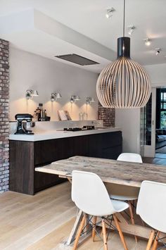 an open kitchen and dining area with brick walls, wood floors, and white chairs