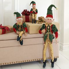 three elf dolls sitting on a couch with presents