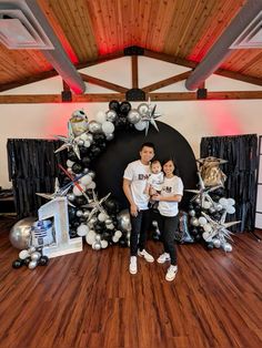 a man and woman standing in front of a balloon arch