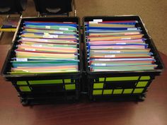 two plastic bins filled with files on top of a table