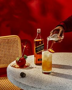 a person pours an apple cider into a glass on a table next to two bottles