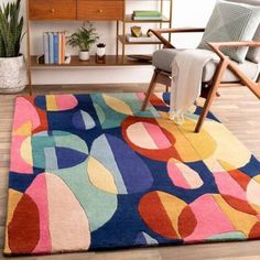 a living room with a colorful rug on the floor and a chair in front of it