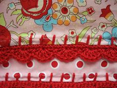 closeup of red and white crocheted material with flowers on pink fabric background