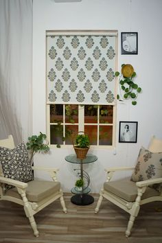 two chairs sitting next to each other in front of a window with pictures on the wall