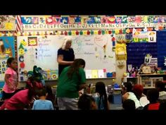 a group of children sitting in front of a whiteboard