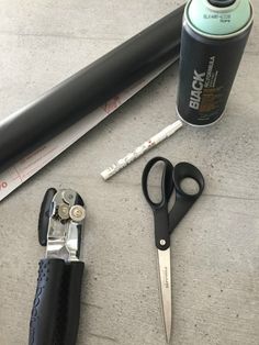 a pair of scissors sitting next to a can and some other items on the ground