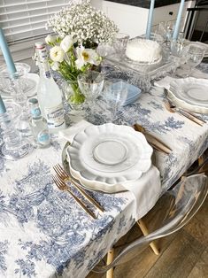 a table set with plates, silverware and flowers in vases on top of it