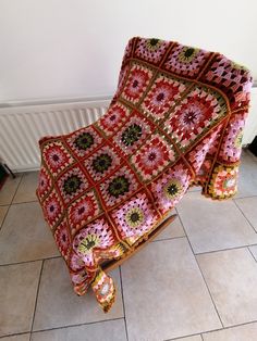 a crocheted blanket sitting on top of a floor next to a radiator