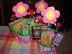 there are many items in the buckets on the table with flowers and candy sticks