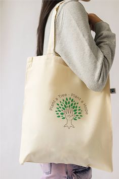 Plant a Tree Plant a Hope - New Design for 2024 Say no to plastic bags and yes to sustainably-sourced organic cotton tote bags! Look good whilst doing good with this gorgeous reusable shopper. Also makes the perfect pressie for lucky friends! At Heikō Clothing we're committed to treating both animals and the planet with compassion and we ensure that all of our products are vegan approved. Product details: * 100% organic certified cotton Tote bag * Professionally printed using environmentally-fri Everyday Organic Recyclable Canvas Bag, Organic Recyclable Canvas Tote Bag, Organic Style Recyclable Canvas Tote Bag, Eco-friendly Recyclable Canvas Tote Bag, Natural Cotton Canvas Bag With Eco-friendly Ink, Organic Recyclable Canvas Bag For Daily Use, Eco-friendly Organic Cotton Canvas Bag For Everyday Use, Organic Recyclable Bags In Natural Color, Organic Recyclable Natural Bags