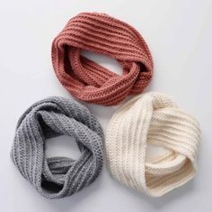 three knitted scarves sitting next to each other on top of a white surface