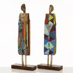 two wooden sculptures with different designs and colors on each one stand next to each other