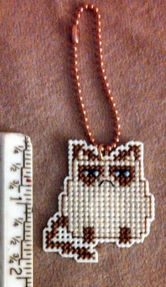 a cross stitch ornament with a ruler next to it