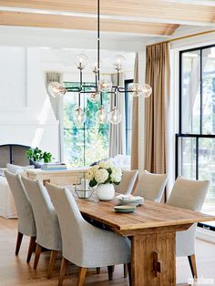 the dining room table is surrounded by chairs and chandelier, with an open fireplace in the background