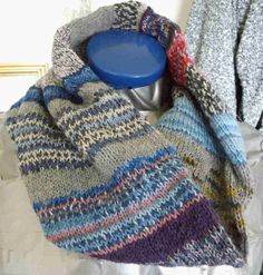 a knitted scarf with a blue plastic cup in the middle and another sweater behind it