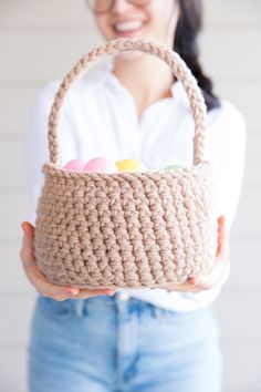 a woman holding a crocheted basket with candy in it