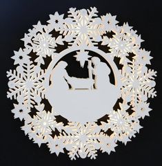 a paper cut nativity scene with snowflakes in the shape of a circle