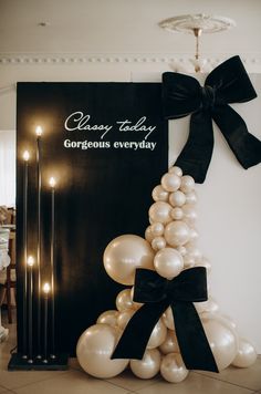 a black and white balloon arch with balloons on it in front of a sign that says classy today gorgeous everyday