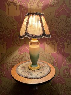 a lamp sitting on top of a table in front of a wallpapered wall