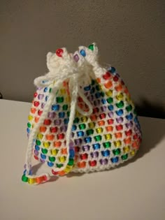 a crocheted bag with multicolored beads sits on a white counter top