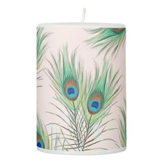 a white candle with green and blue feathers on it