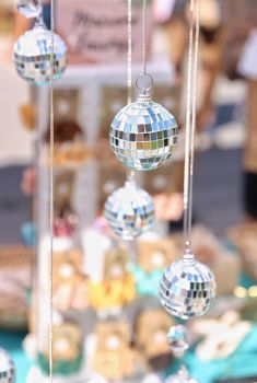 several disco ball ornaments hanging from chains in front of a table filled with other items