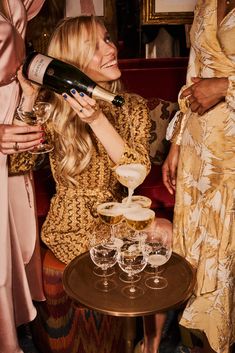 a woman pouring champagne into wine glasses on a table